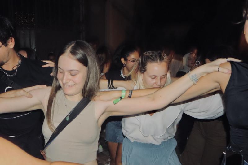 A group of volunteers holding each other's arms and dancing traditional dances