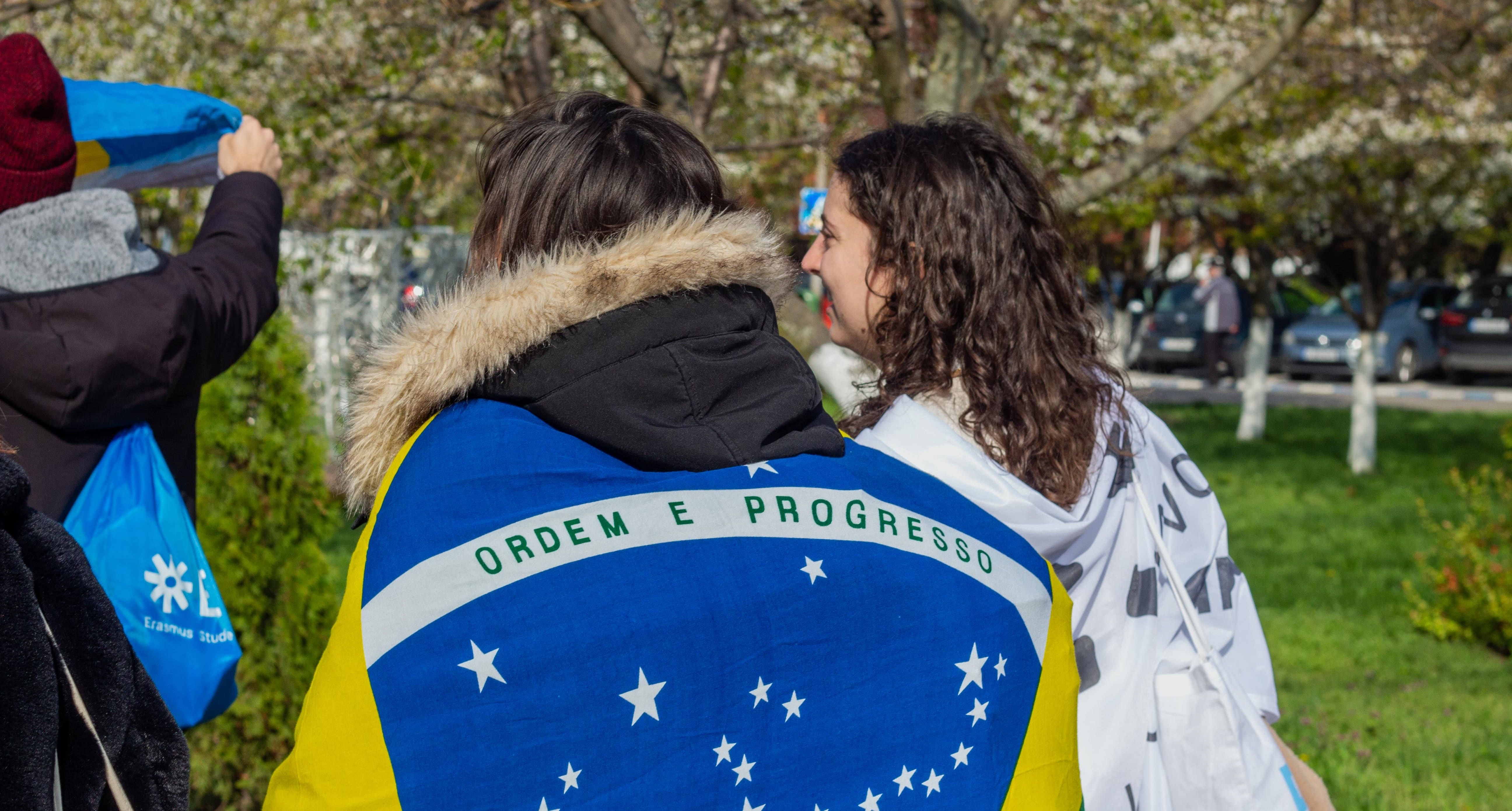 A photo of two people from the back wrapped in flags.