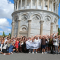 A big group of people posing for a photo in front of the Leaning Tower of Pisa.