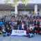 A big group of people posing for a picture with a flag of ESN Greece.