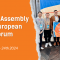 Image with orange background. On the left side is the text: "General Assembly of the European Youth Forum", followed by the location and the date of the event. On the right side there is an image with 7 young men who hold a flag that has the text "for youth rights" on it.