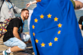 A picture of young people and an EU flag in front of them.