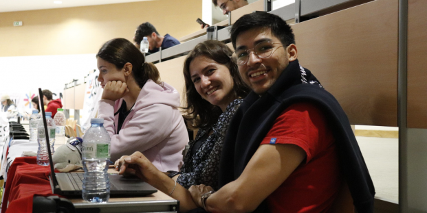 A photo of two students sitting in a classroom and smiling towards the camera.